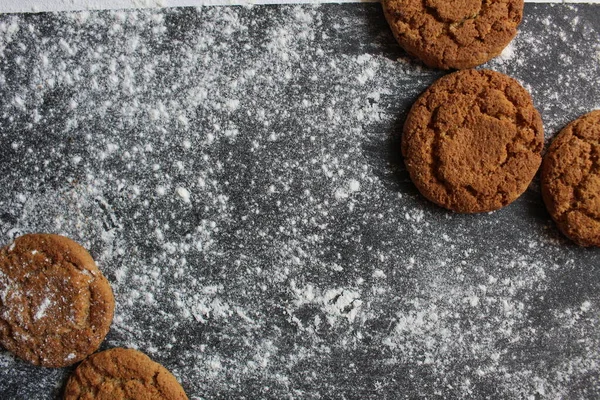 homemade oatmeal cookies on a dark gray background dusted with powdered sugar