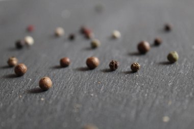 Beyaz ekmek ve füme sosisli sandviçle dolu gri siyah taş bir masada biberin yanında. 