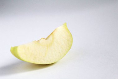 Sol taraftaki beyaz gri arkaplanda bir parça elma dilimle.