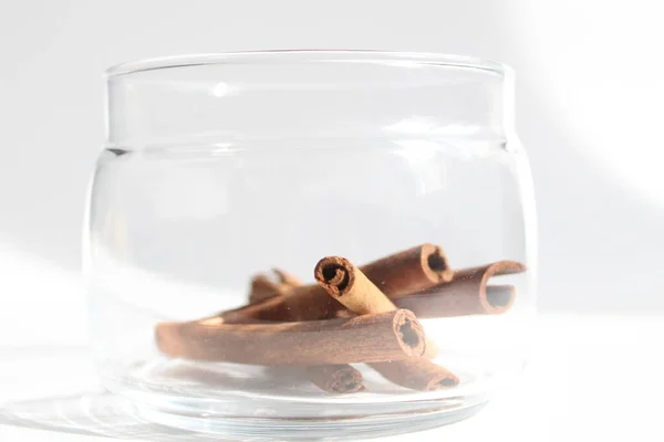 a few sticks of cinnamon lie in a clear glass jar on a white background with a place to insert for text or product item