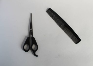 Beyaz arkaplanda berber tarağı ve makas