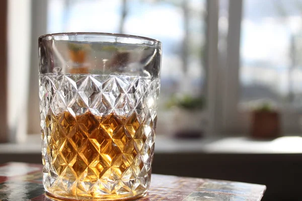 玻璃杯上有威士忌或白兰地的玻璃杯 放在白底的桌子上 太阳光照射着玻璃杯的侧面 — 图库照片