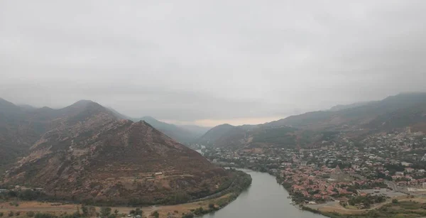 タマラ女王の街からの眺めジョージア 川は雲や霧で曇り空の街の風景の右側に山の左側の2つの支流に分かれています — ストック写真