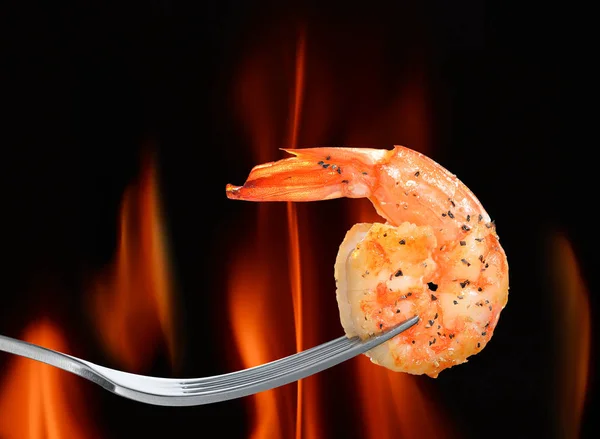 Camarones cocidos, langostinos sobre tenedor sobre fondo de llama —  Fotos de Stock