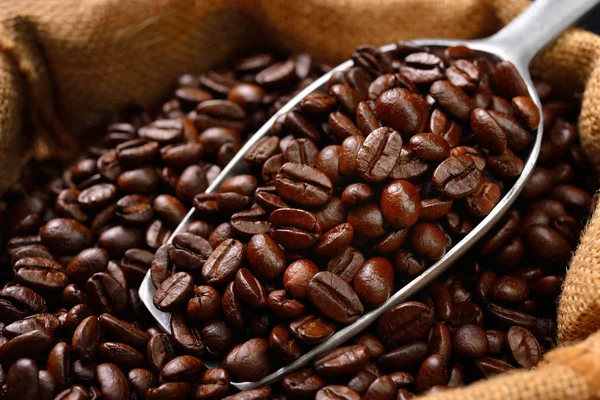 Grãos de café e colher em saco de serapilheira — Fotografia de Stock