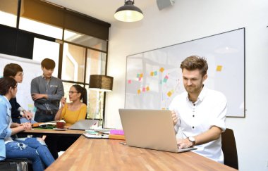 Bir dizüstü bilgisayar ofiste gülümseyen genç işadamı