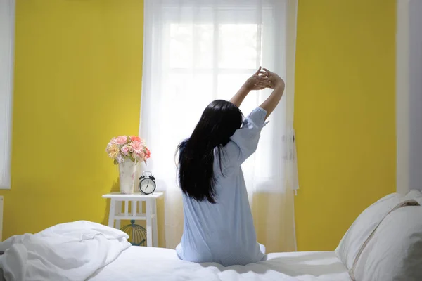 Kobieta rozciągająca się w łóżku po przebudzeniu, widok z tyłu — Zdjęcie stockowe