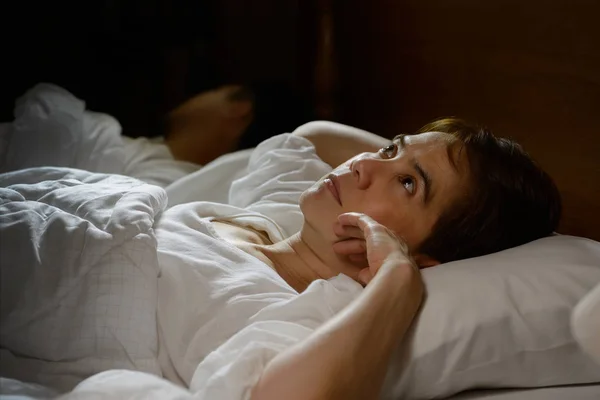 Kobieta z bezsennością leżąca w łóżku z otwartymi oczami — Zdjęcie stockowe