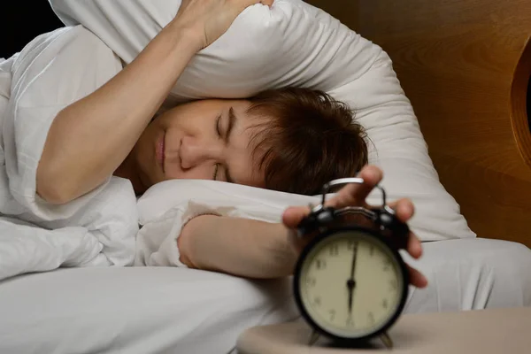 Vrouw het uitschakelen van de wekker op het bed — Stockfoto