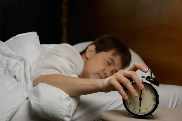 Vrouw het uitschakelen van de wekker op het bed — Stockfoto