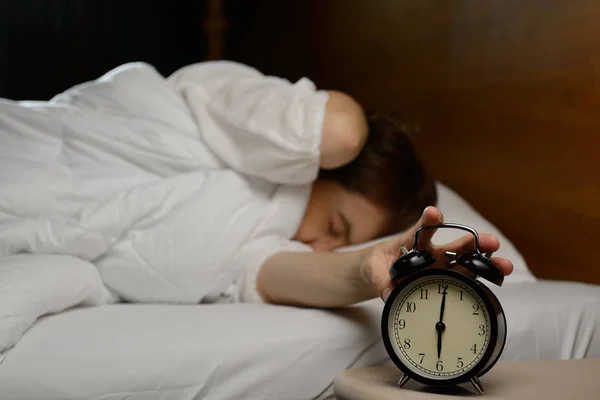 女性がベッドの上の目覚まし時計をオフにします。 — ストック写真