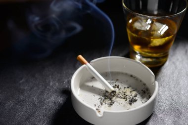 Kül tablası bardak viski ile aydınlatılmış ve sigara sigara
