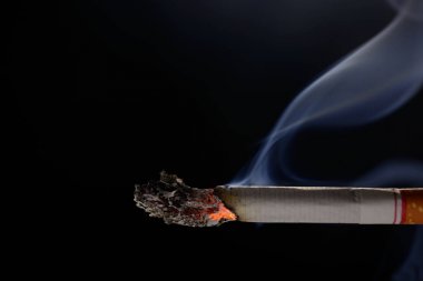 Siyah arka plan üzerinde duman ile aydınlatılmış ve yanan sigara