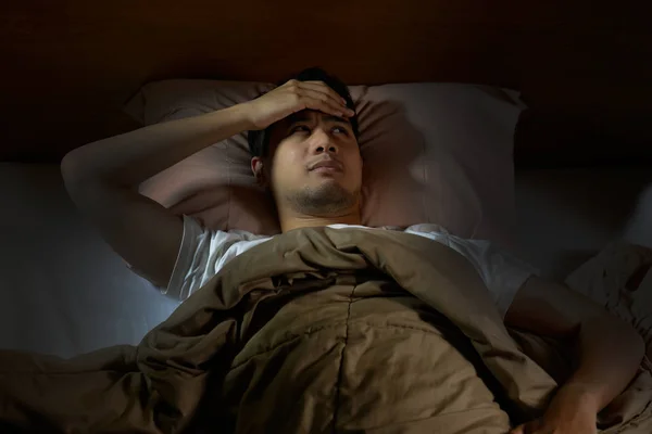 Przygnębiony człowiek cierpi na bezsenność, leżąc w łóżku — Zdjęcie stockowe