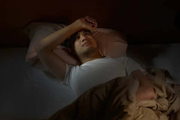 Przygnębiony człowiek cierpi na bezsenność, leżąc w łóżku — Zdjęcie stockowe