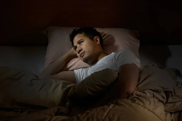 Депресивний чоловік, який страждає від безсоння лежить у ліжку — стокове фото