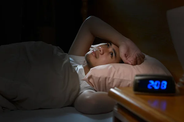 Depressed man suffering from insomnia lying in bed