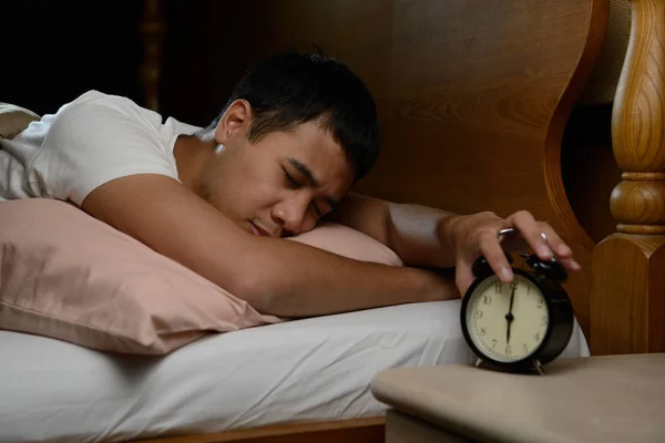 Jeune homme éteignant le réveil sur le lit — Photo