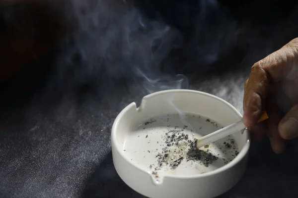 Mano poniendo el cigarrillo en un cenicero —  Fotos de Stock