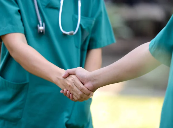 Médicos en un equipo médico saludan juntos al aire libre en el gree —  Fotos de Stock