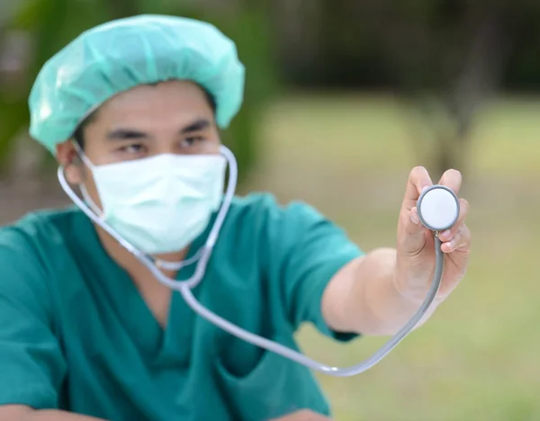 Ritratto di medico asiatico che utilizza lo stetoscopio sullo sfondo del parco verde — Foto Stock