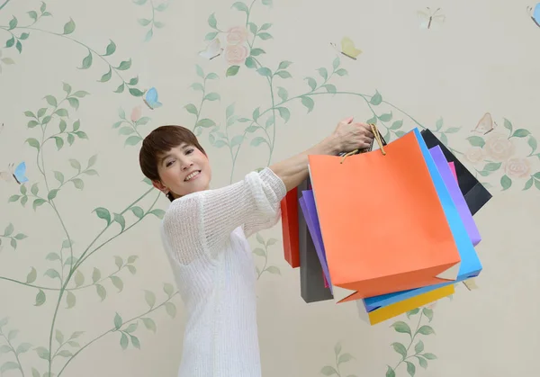 Gelukkige vrouw in het winkelcentrum holding boodschappentassen en glimlachen — Stockfoto