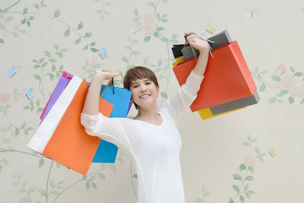 Gelukkige vrouw in het winkelcentrum holding boodschappentassen en glimlachen — Stockfoto