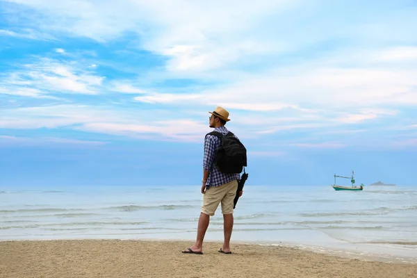 Νεαρός ταξιδιώτης άνδρα με σακίδιο στέκεται στο παραθαλάσσιο και ψάχνει να τον ωκεανό — Φωτογραφία Αρχείου