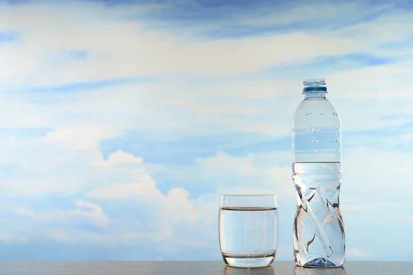 Świeże i czyste wody pitnej w butelki i kieliszki na tle nieba — Zdjęcie stockowe