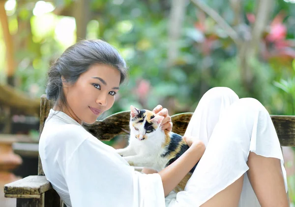 Genç bir kadın ile bir kedi Bahçe koltuk üzerinde dinleniyor