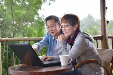 Yeşil bahçe arka plan ile dizüstü bilgisayar evde kullanan mutlu üst düzey Çift