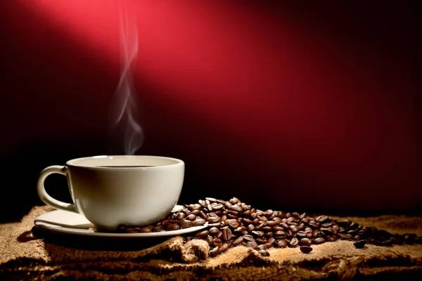 杯咖啡与烟雾和咖啡豆红棕色背景 — 图库照片