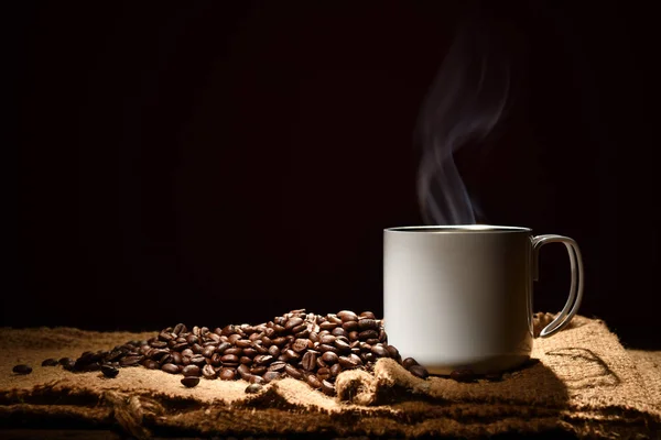 黒い背景に煙とコーヒー豆とコーヒーのカップ — ストック写真