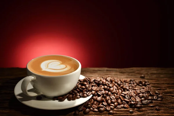 Cup of coffee latte and coffee beans on reddish brown background