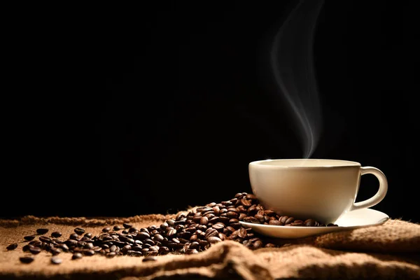 木製の背景の煙とコーヒー豆とコーヒーのカップ — ストック写真