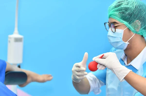 Asian male obstetrician and nurse are delivered to the patient lying on a bed in the delivery room of the hospital