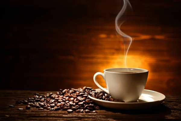 古い木の背景に煙とコーヒー豆とコーヒーのカップ — ストック写真