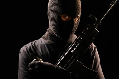 Makineli tüfek ve el bombası siyah arka plan üzerine tutarak soyguncu
