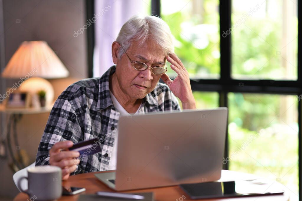 Asian senior man looking confuse when using credit card for online shopping