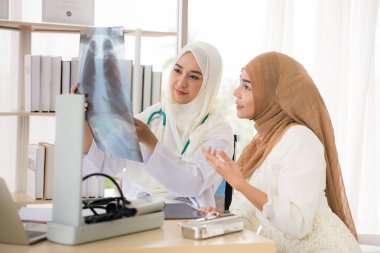 Müslüman kadın doktor hastaya röntgen sonuçlarını anlatıyor.