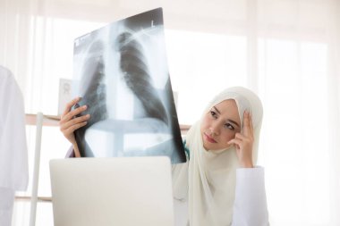 Muslim woman medical doctor looking at x-rays result in a hospital clipart