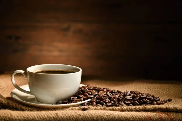 Tasse Kaffee Und Kaffeebohnen Auf Kleesack Auf Altem Holzgrund — Stockfoto
