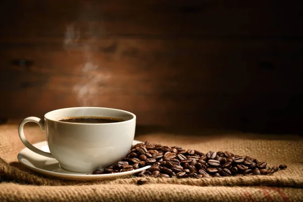 用烟熏咖啡和咖啡豆包在旧木背上的咖啡杯 — 图库照片