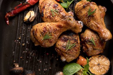 Tavada çeşitli sebzelerle ızgara tavuk budu.