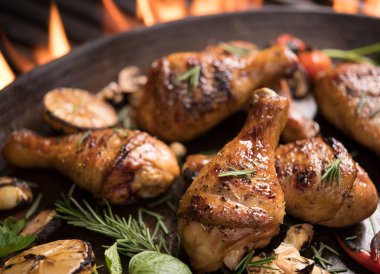 Kızarmış tavuk budu ve tavada çeşitli sebzeler.