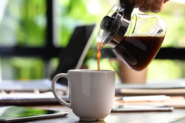 Eine Hand Gießt Dampfenden Kaffee Eine Tasse Auf Einem Schreibtisch — Stockfoto