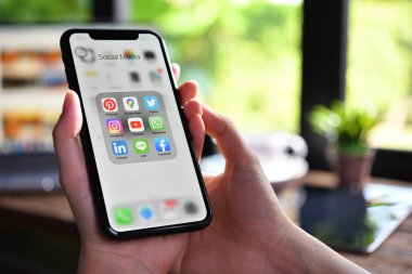 BANGKOK, THAILAND - 30 Mart 2020: Kafeteryadaki ekranda sosyal medya simgeleriyle Iphone xr 'yi tutan kadın.