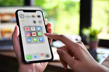 BANGKOK, THAILAND - 30 Mart 2020: Kafeteryadaki ekranda sosyal medya simgeleriyle Iphone xr 'yi tutan kadın.