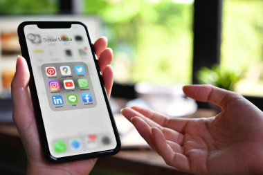 BANGKOK, THAILAND - 30 Mart 2020: Kafeteryadaki ekranda sosyal medya simgeleriyle Iphone xr 'yi tutan kadın.