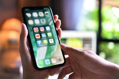BANGKOK, THAILAND - 30 Mart 2020: İphone XR 'yi elinde tutan kadın evde ekranda sosyal medya simgeleri var